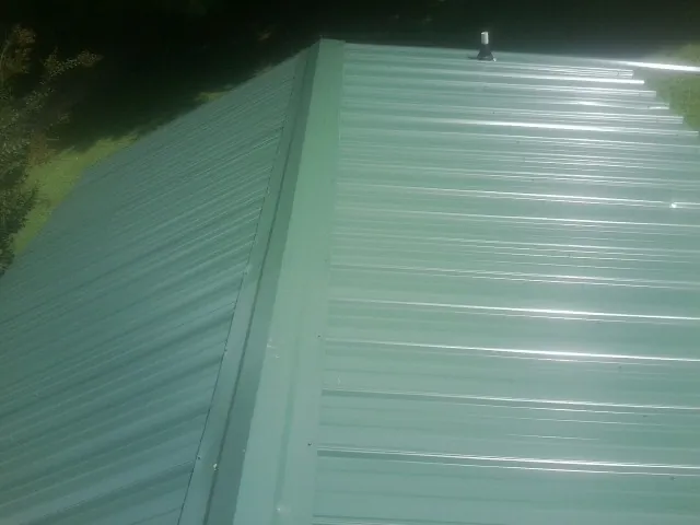 New green metal panels meeting at the ridge of a roof — Flat Roof Repair work by our crew in Storrs Mansfield