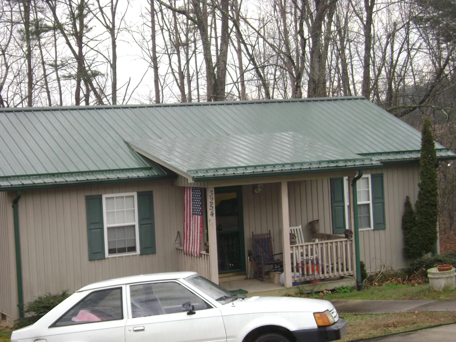 Green metal roof and front porch on a tan sided cottage in Storrs Mansfield