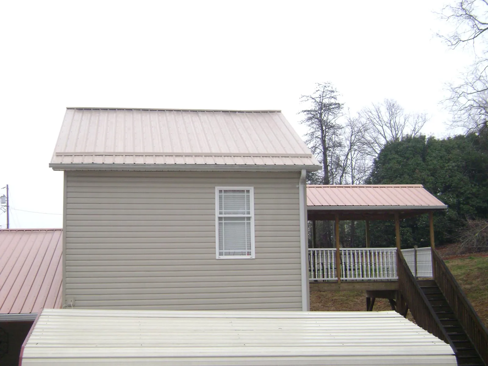 Tan metal roofs on a two story addition and attached porch, from a Roof Replacement job in Storrs Mansfield