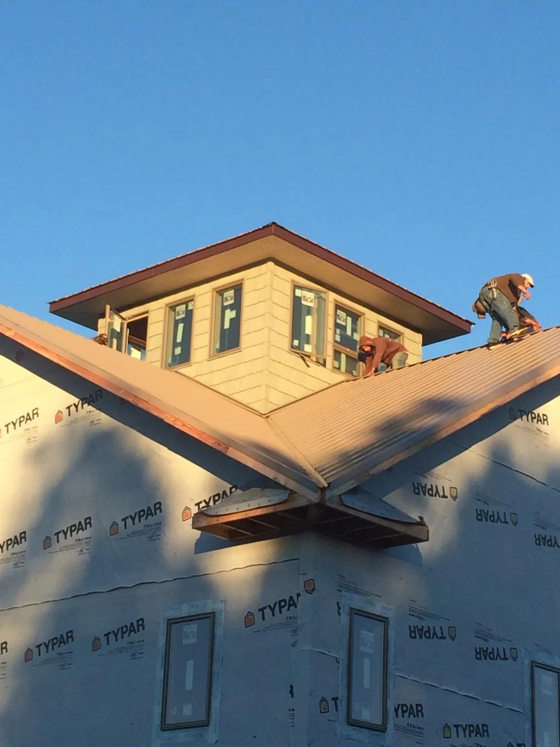Roofers working around a rooftop cupola on a new metal roof at sunset — Roof Waterproofing in Storrs Mansfield by Roofing Brothers